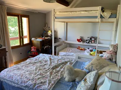 a small white dog sitting on a bed in a bedroom at Maison provençale en campagne à Eguilles in Éguilles