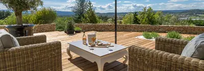 a patio with a table and chairs on a wooden deck at Villa Domitia Chambre d'Hôtes Luberon in Bonnieux