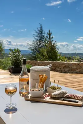 a table with a bottle of wine and a glass at Villa Domitia Chambre d'Hôtes Luberon in Bonnieux