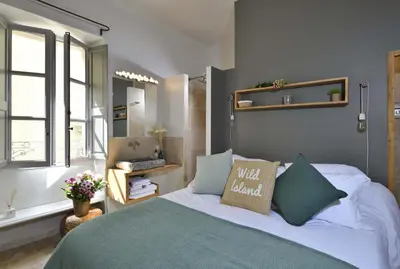 a bedroom with a bed with a green blanket at La Maison de Lourmarin in Lourmarin