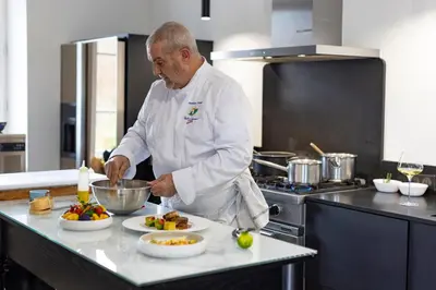 a man standing in a kitchen preparing food at La Bastide de Damien, 5 clefs Demeure d'Exception et Table Remarquable dans le guide Teritoria, JACUZZI Privatif, Cuisine étoilée Dominique Frérard in Aix-en-Provence
