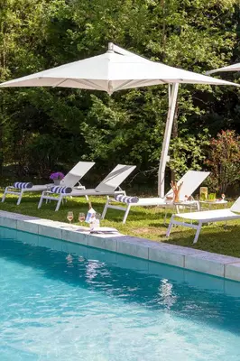 a group of lounge chairs and an umbrella next to a pool at La Bastide de Damien, 5 clefs Demeure d'Exception et Table Remarquable dans le guide Teritoria, JACUZZI Privatif, Cuisine étoilée Dominique Frérard in Aix-en-Provence
