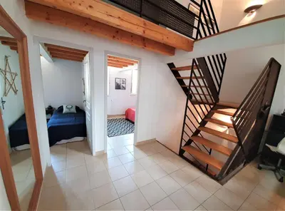 a room with a staircase and a bedroom with a bed at Maison de village façon Loft, avec cour et airco, dans le centre historique in LʼIsle-sur-la-Sorgue