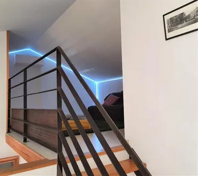 a room with a staircase with a blue light at Maison de village façon Loft, avec cour et airco, dans le centre historique in LʼIsle-sur-la-Sorgue