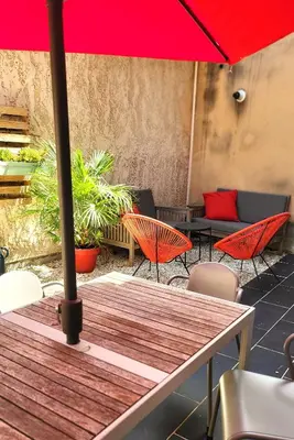 a table with a red umbrella on a patio at Maison de village façon Loft, avec cour et airco, dans le centre historique in LʼIsle-sur-la-Sorgue