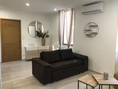 a living room with a brown couch and a mirror at Gite au cœur du ventoux in Bédoin