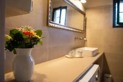 a white vase with flowers on a counter in a bathroom at Bastide Toujours Dimanche, Maison de vacances avec vue & piscine chauffée in Gordes
