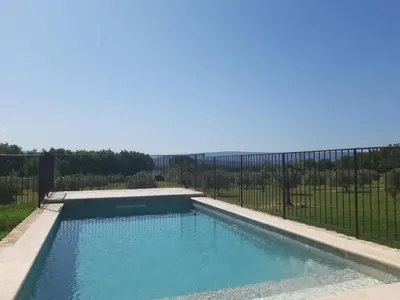 a swimming pool in front of a fence at Bastide Toujours Dimanche, Maison de vacances avec vue & piscine chauffée in Gordes