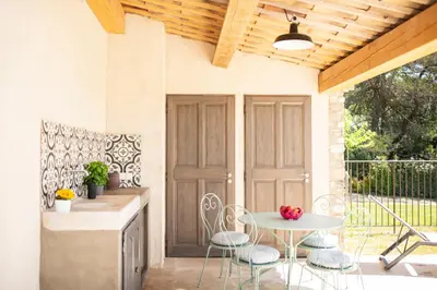 a patio with a table and chairs and a door at Bastide Toujours Dimanche, Maison de vacances avec vue & piscine chauffée in Gordes