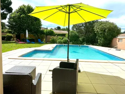 a yellow umbrella sitting next to a swimming pool at Villa et maisonnette provençales in Carpentras