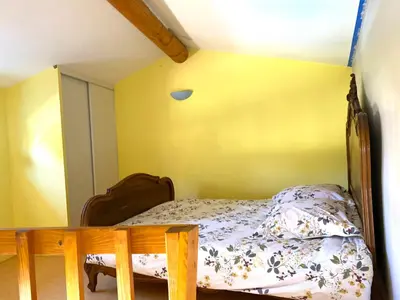 a bedroom with a bed and a yellow wall at Villa et maisonnette provençales in Carpentras