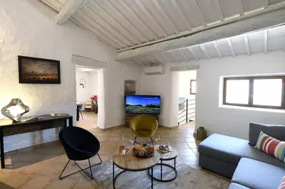 a living room with a couch and chairs and a tv at Gite des Demoiselles in Roussillon
