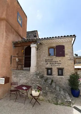 a building with two chairs and a table in front of it at Gite des Demoiselles in Roussillon