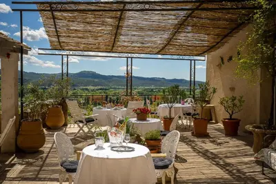 a patio with white tables and chairs and a view at La Chaumière, Demeure d'hôtes in Lauris