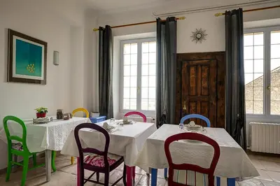a dining room with two tables and colorful chairs at La Chaumière, Demeure d'hôtes in Lauris