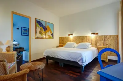 a bedroom with a bed and a table and chairs at La Chaumière, Demeure d'hôtes in Lauris