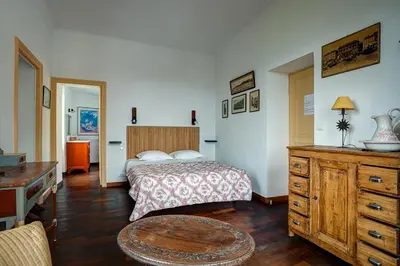 a bedroom with a bed and a desk and a table at La Chaumière, Demeure d'hôtes in Lauris