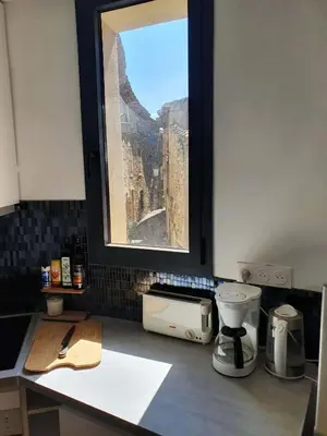 a kitchen with a view of a city from a window at L'Exquishette de Lourmarin, un nid sur les toits. in Lourmarin