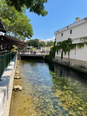 a river next to a building and a bridge at Appartement et Garage au Cœur de l'Isle in LʼIsle-sur-la-Sorgue