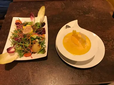 two plates of food and a bowl of soup on a table at Hostellerie Le Mirabeau in Peyrolles-en-Provence