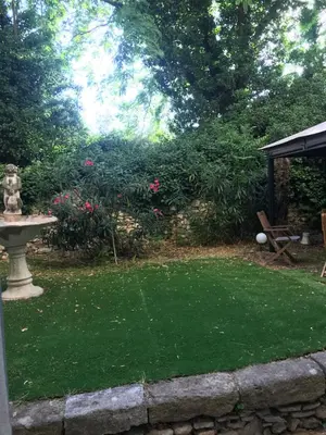 a garden with a lawn with a fountain and a bench at Le jardin in Aix-en-Provence