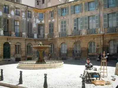 a man sitting in a chair in front of a fountain at Le jardin in Aix-en-Provence