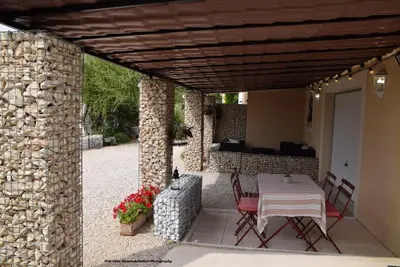 a patio with a table and chairs and a stone wall at Chez Mamou & Dadou in Monteux