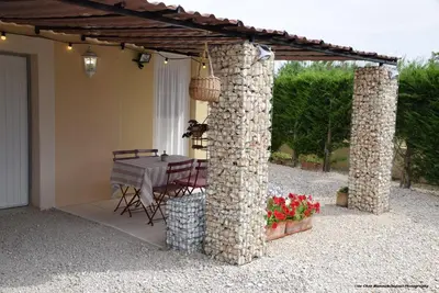a patio with a table under a stone pergola at Chez Mamou & Dadou in Monteux