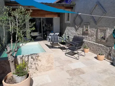 a patio with a pool and chairs and a house at Gîte 