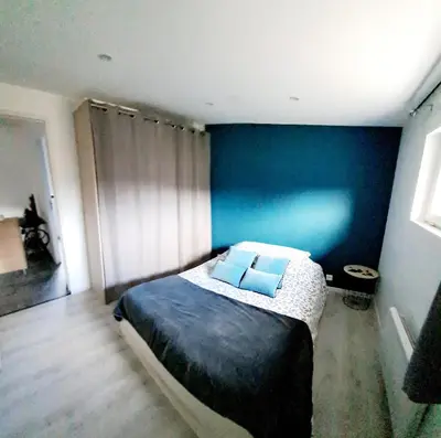 a bedroom with a bed with a blue wall at Gîte 