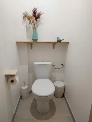 a white bathroom with a toilet and a vase of flowers at La ferme des Escampades in Monteux