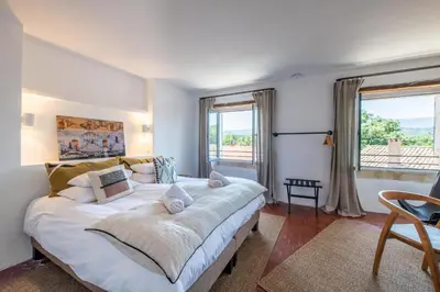 a bedroom with a large white bed and windows at Au Ralenti du Lierre in Beaumettes