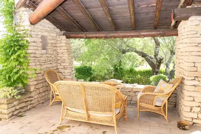 an outdoor patio with wicker chairs and a table at VILLA PROVENCALE FACE AU LUBERON in Cabrières-dʼAvignon