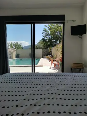 a bedroom with a bed and a view of a pool at chambre d hotes la dragonne in Maubec