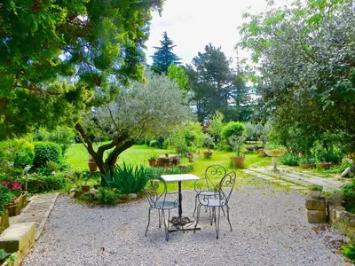 a table and chairs in the middle of a garden at le vieux pont in Carpentras