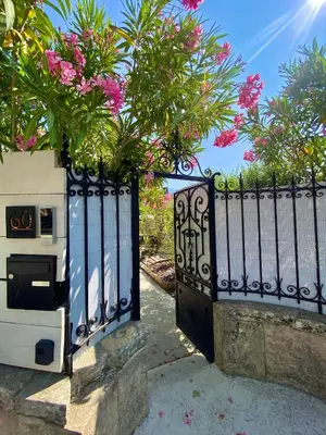 a black gate with pink flowers on top of it at La maison Gerval in Bédoin