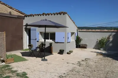 a patio with an umbrella in front of a building at Les BRUNS in Saignon
