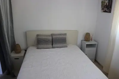 a small bedroom with a white bed with two night stands at Les BRUNS in Saignon