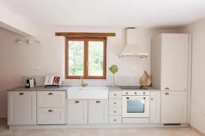 a kitchen with white cabinets and a window at La Petite Ruche, 1 bedroom Gite in the Luberon in Apt