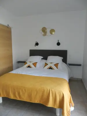 a bedroom with a white bed with a yellow blanket on it at L’ escapade in Mallemort