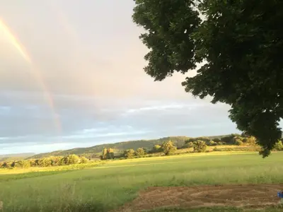 a rainbow in the sky over a green field at Chambre hôtes Les Garrigues CUCURON in Cucuron
