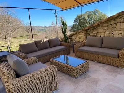 a patio with wicker furniture and a stone wall at Bastide provençale à Murs, coeur du Lubéron in Murs