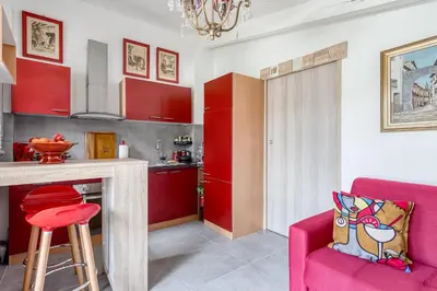 a kitchen with red cabinets and a pink chair at Le Parc in Carpentras