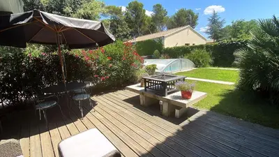 a wooden deck with a bench and an umbrella at Le Parc in Carpentras