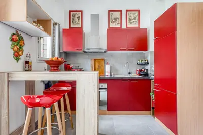a red kitchen with red cabinets and red stools at Le Parc in Carpentras