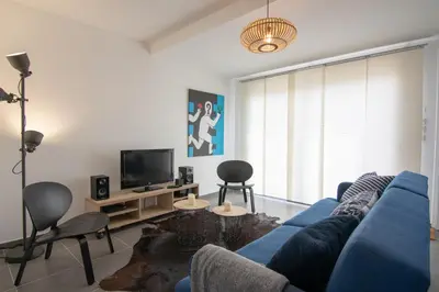 a living room with a blue couch and a tv at L'Isle Ô Jardin in LʼIsle-sur-la-Sorgue