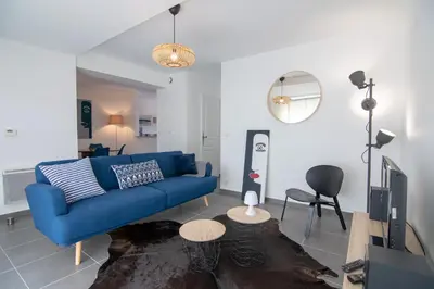 a living room with a blue couch and a tv at L'Isle Ô Jardin in LʼIsle-sur-la-Sorgue