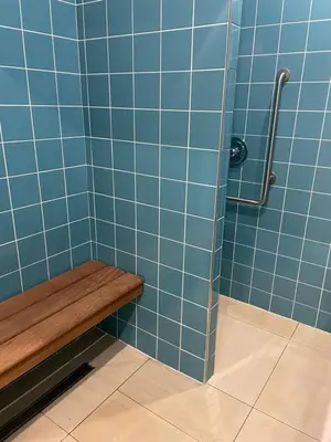 a blue tiled shower with a wooden bench in a bathroom at DOMITYS LES TOURMALINES in Carpentras