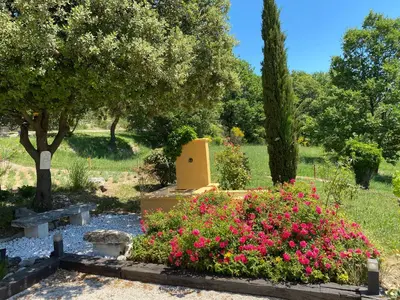 a garden with pink flowers and a grave at Location bastide provencale Luberon in Murs