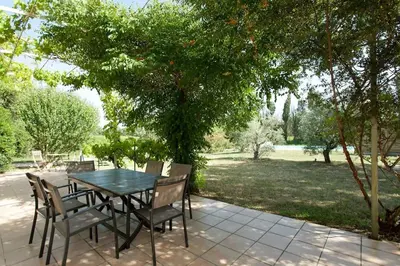 a table and chairs on a patio under a tree at LA LEZARDIERE CHEZ HUGUES in Saint-Rémy-de-Provence